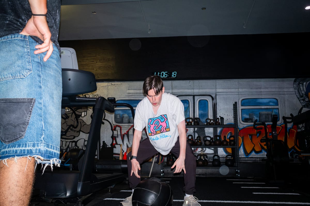Person training with a medicine ball beside the subway mural at GYM NYC Mulberry